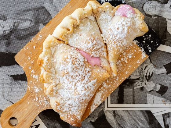 Nutella and marshmallow calzone dusted with icing sugar on a wooden board